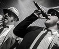 This image shows two men dressed as The Blues Brothers. They are singing.