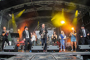 This image is of a Blues Brothers tribute band perforing at FeastyFest, Cheam Park in September 2022. There are audience members on stage too.