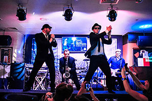 This image shows two men centre stage at The Huddle Sports Bar, Bur Dubai, 2016 performing as The Blues Brothers (TM).