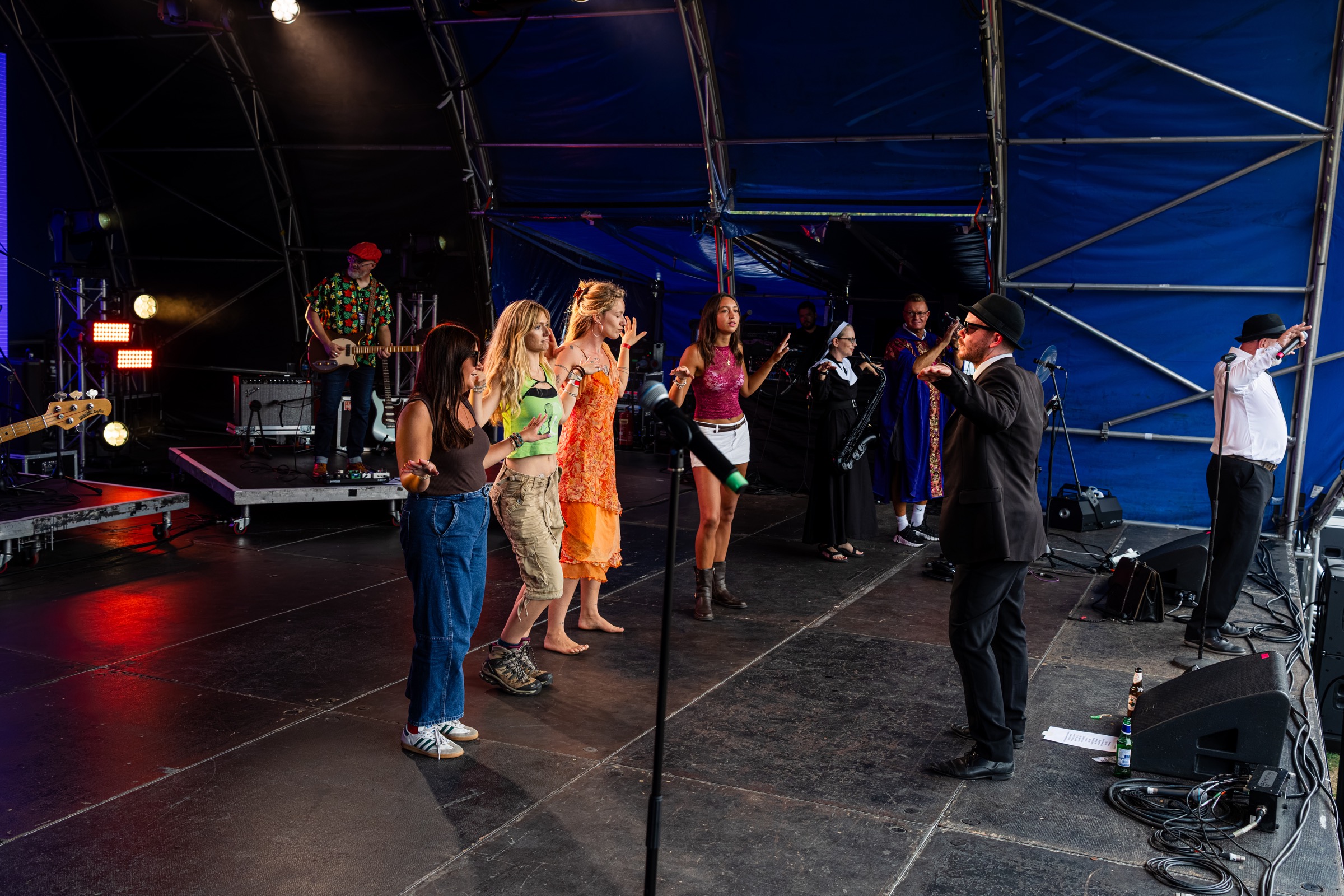 The band performing with guest dancers on a brightly lit festival stage